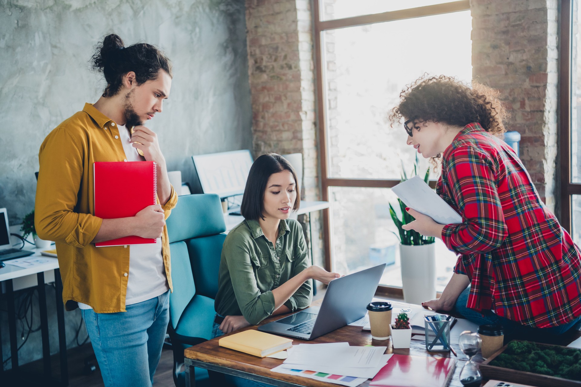 Young professionals collaborating in a modern workspace, focusing on teamwork and innovation in a creative office environment